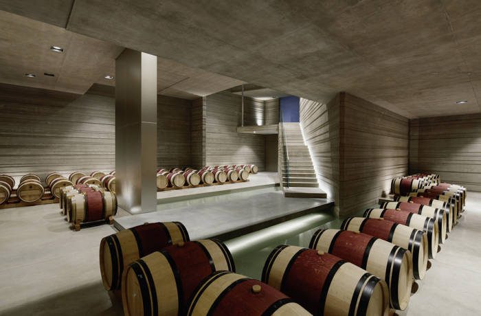 Underground wine cellar with wooden barrels and concrete walls and ceilings