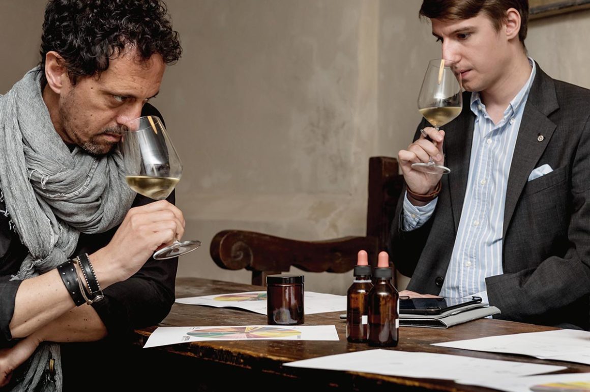 Two men sniffing a glass of white wine in a restaurant
