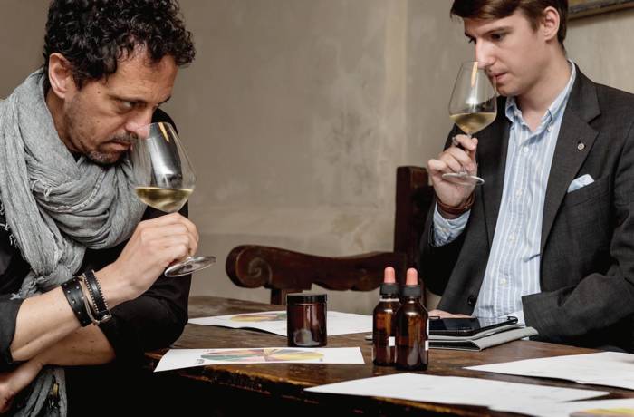 Two men sniffing a glass of white wine in a restaurant
