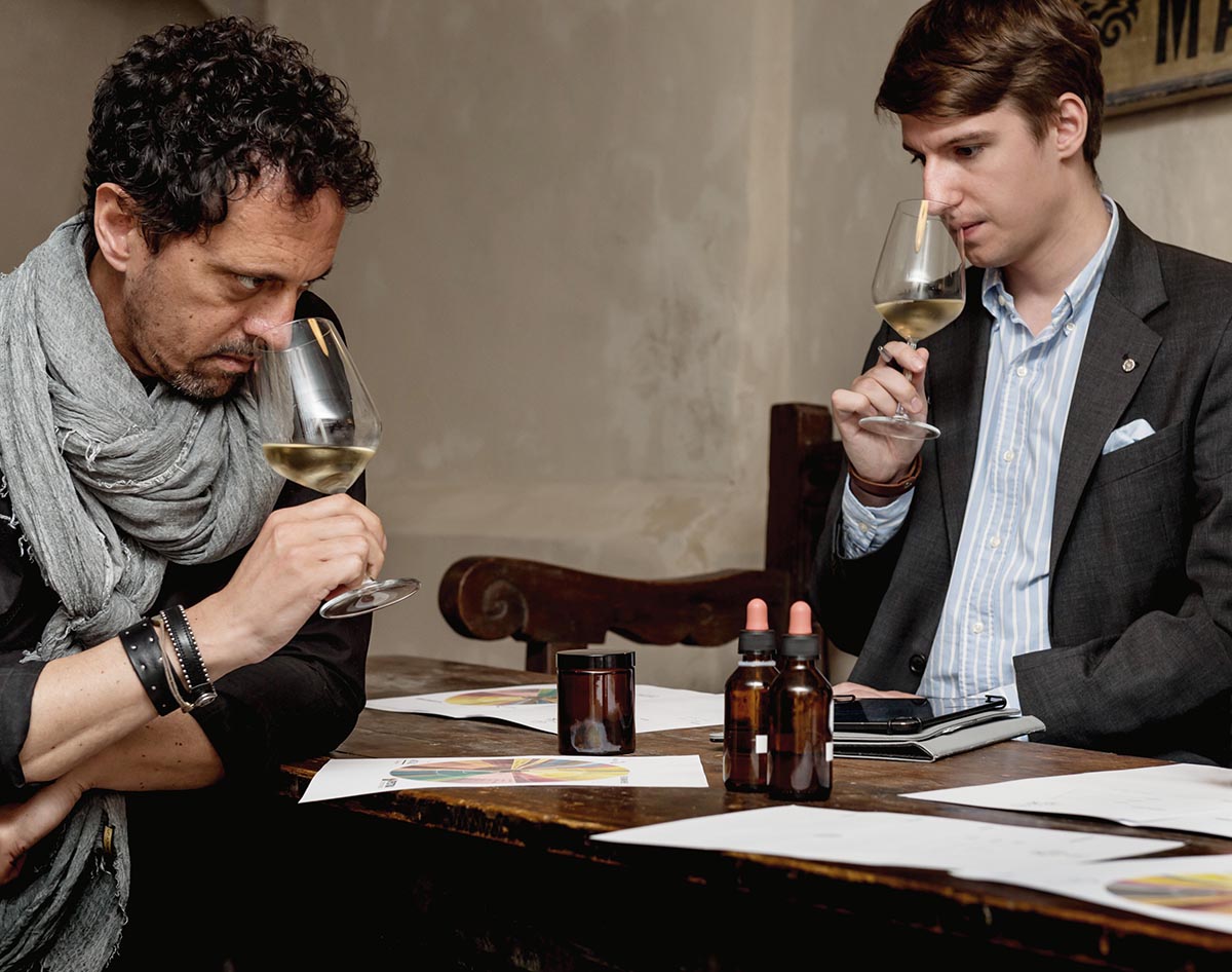 Two men sniffing a glass of white wine in a restaurant