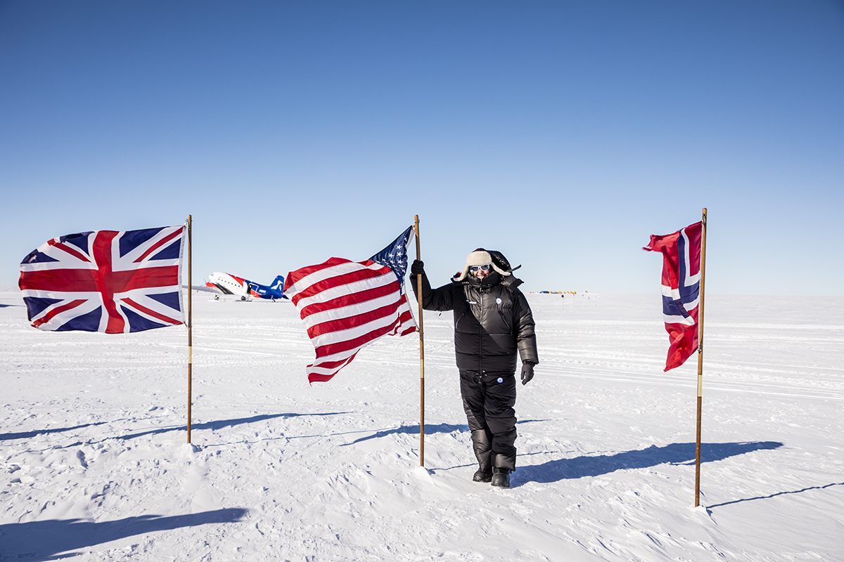 Man standing at South Pole wit American flag