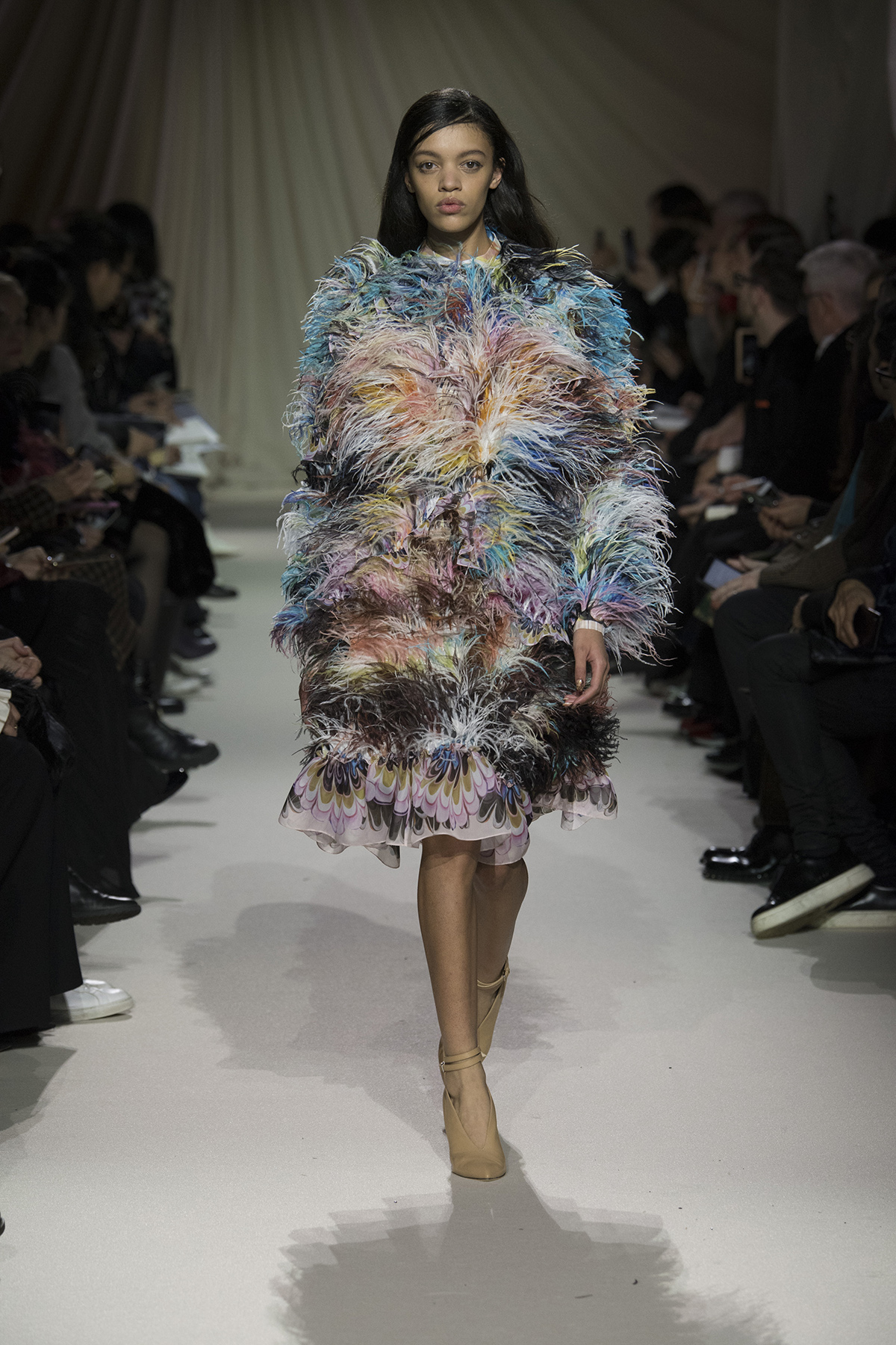Model on the catwalk wearing a large multicoloured coat