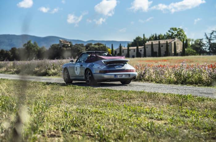 Classic car driving along a country road in the French countryside