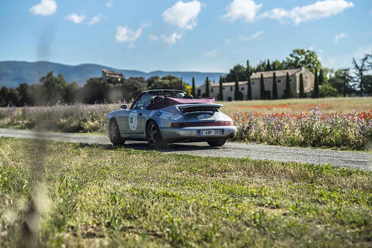 Classic car driving along a country road in the French countryside