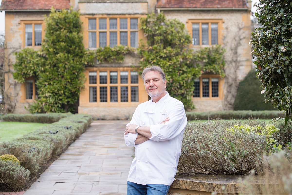 Famous chef Raymond Blanc standing in a country estate garden