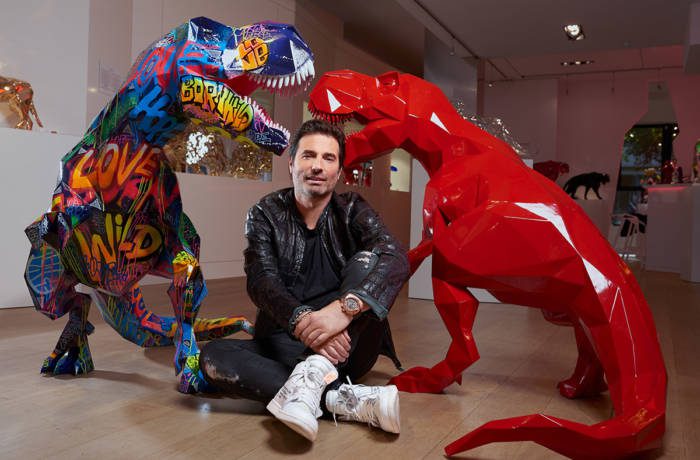 Man sitting on the floor in front of sculptures of dinasours