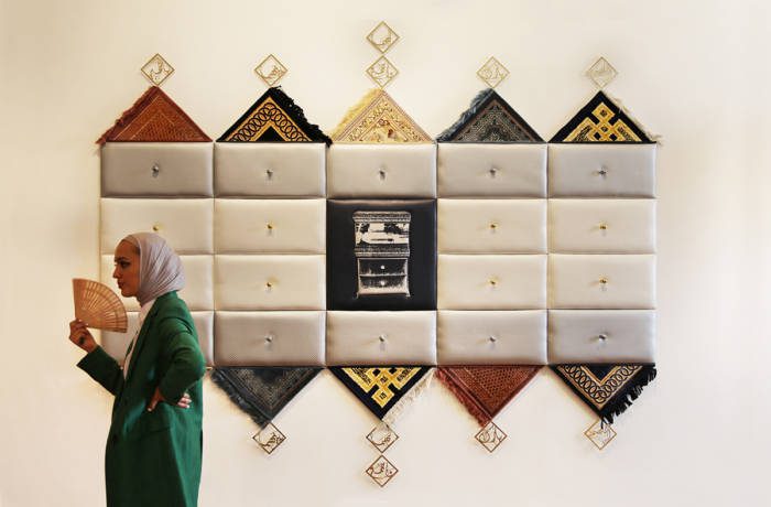 Woman walks in front of an artwork fanning herself