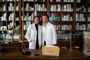 A man and a woman wearing lab coats in an old shop
