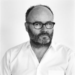 Portrait photograph of a man wearing a white shirt and glasses