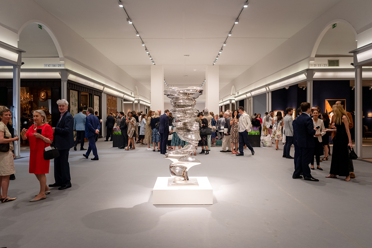 Installation shot of an art fair with guests walking around a sculpture