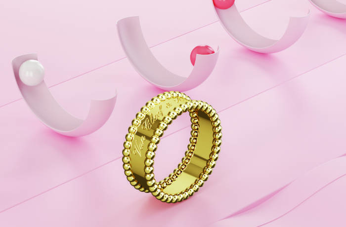 A gold ring on a pink surface with half pink circles in the background