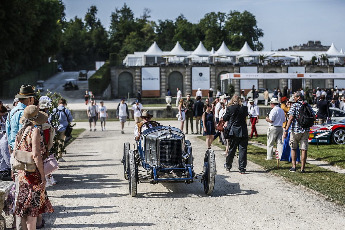 Classic car driving through crowds