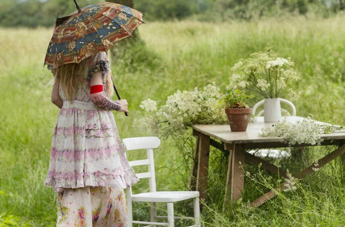 Woman walking towards table wearing a smart dress and holding a parasol