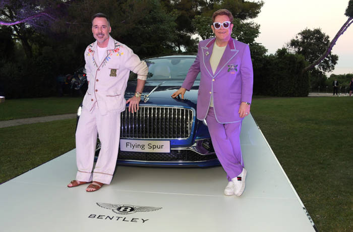 Sir Elton John standing with a Bentley sports car