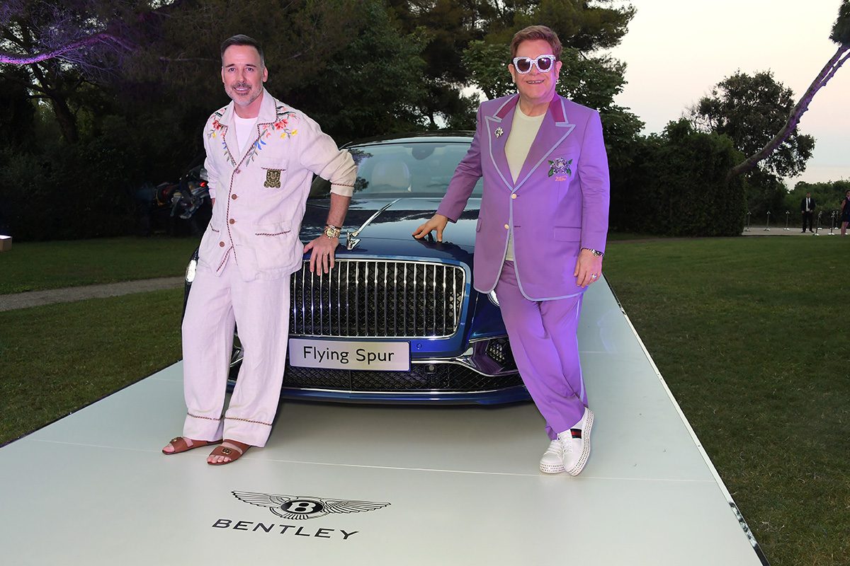 Sir Elton John standing with a Bentley sports car