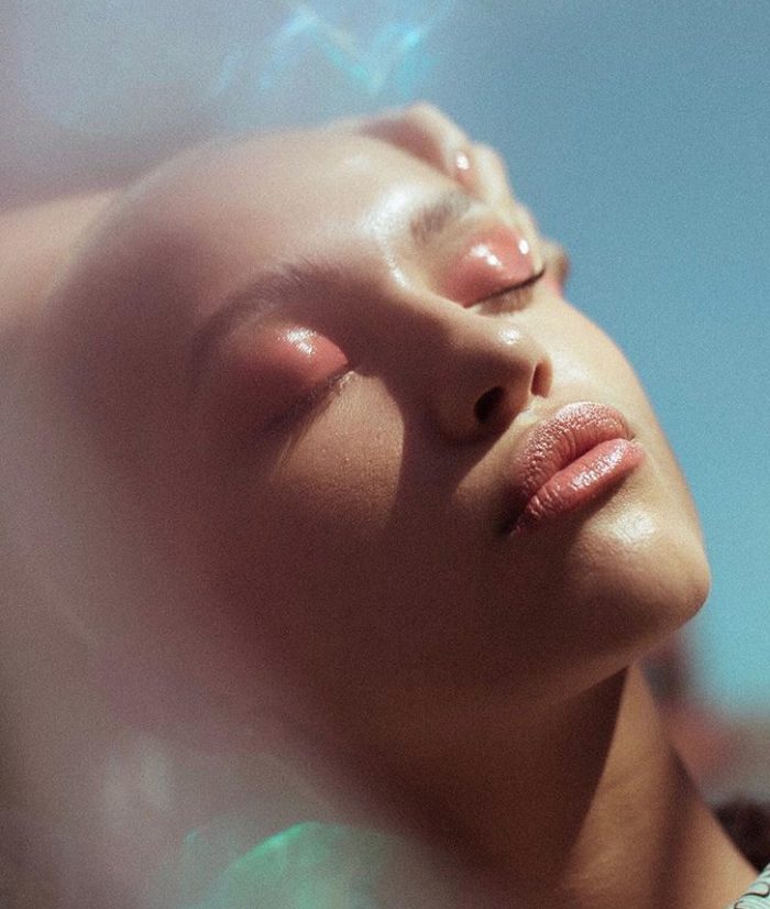 Close up shot of a female model wearing pink eye shadow with eyes closed