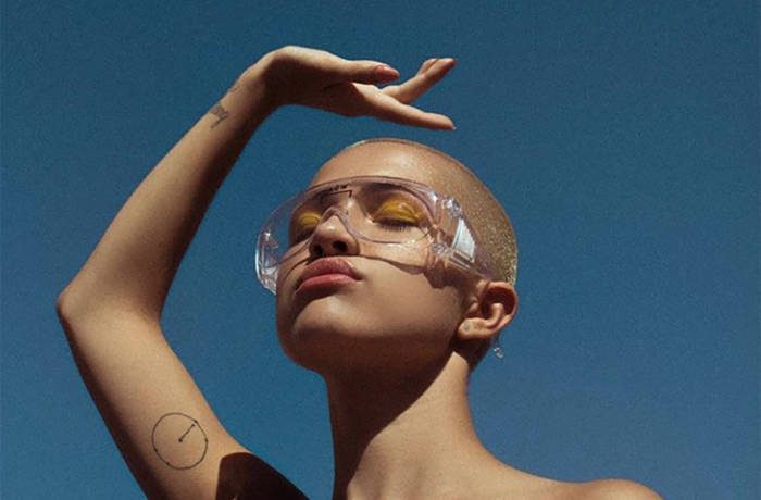 Shave head female model against blue sky