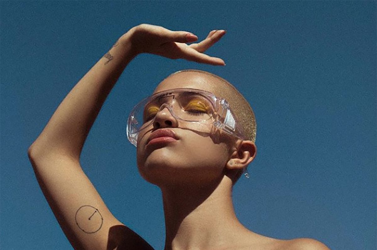 Shave head female model against blue sky