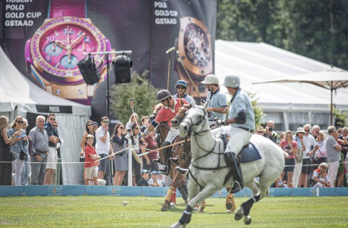 Polo players mid match with sticks raised