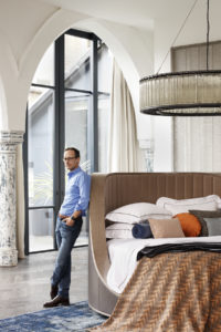 Man leaning against the edge of a bed in a showroom