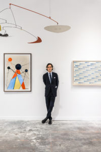 Man standing in a suit amidst contemporary art works