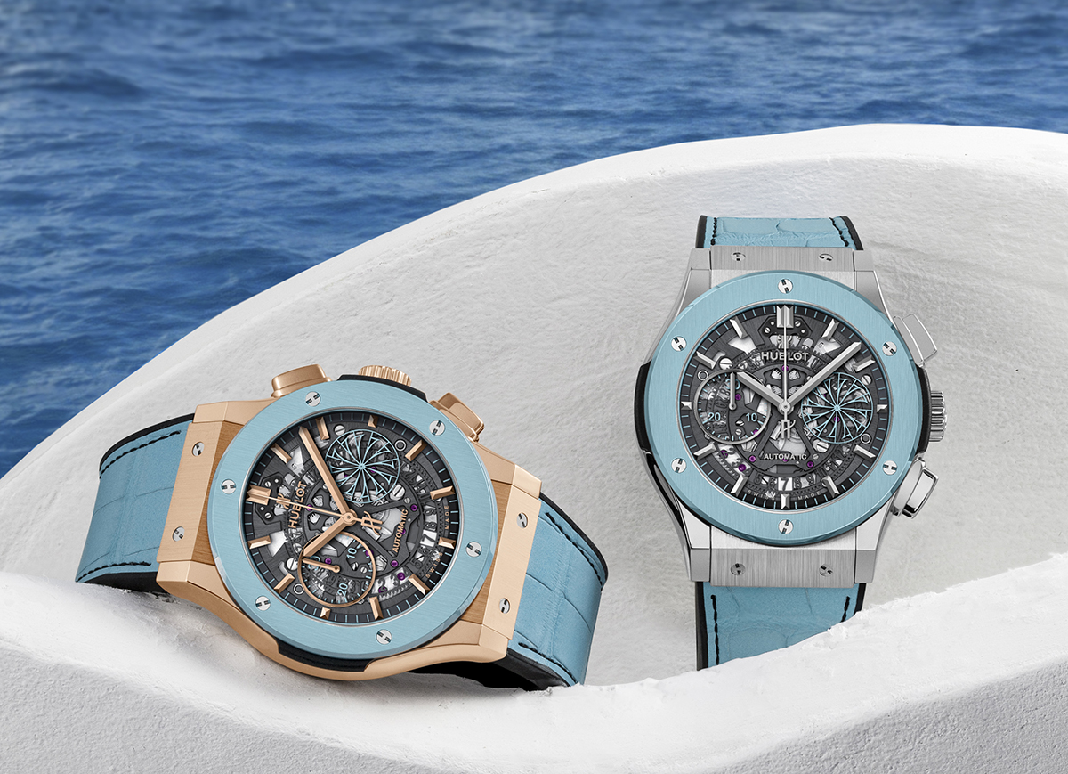 Two watches resting on a white wall with ocean in background