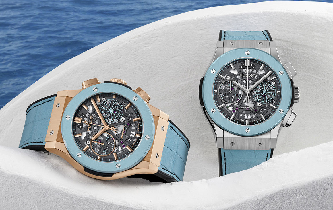 Two watches resting on a white wall with ocean in background