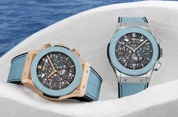 Two watches resting on a white wall with ocean in background