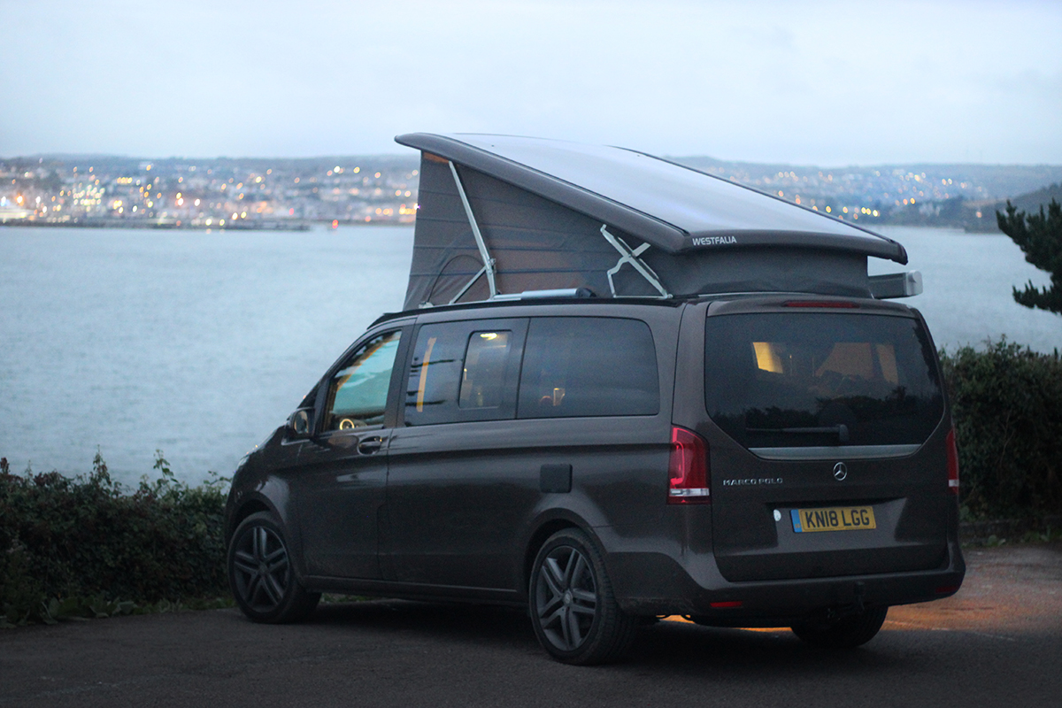 luxurious camper van with pop up roof and ocean in distance