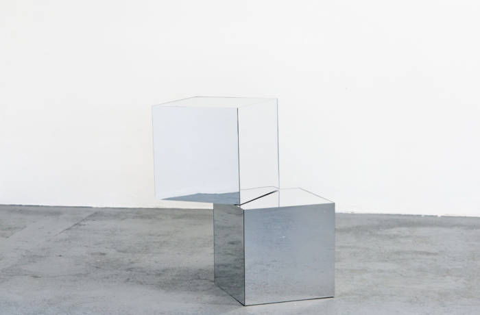 Two reflective boxes stacked on top of each other in a white room