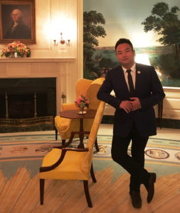 Man leaning against a hotel chair in a suit