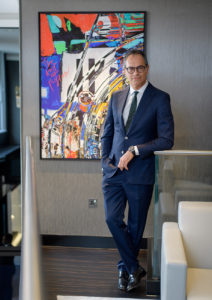 Man in a suit standing by an abstract artwork