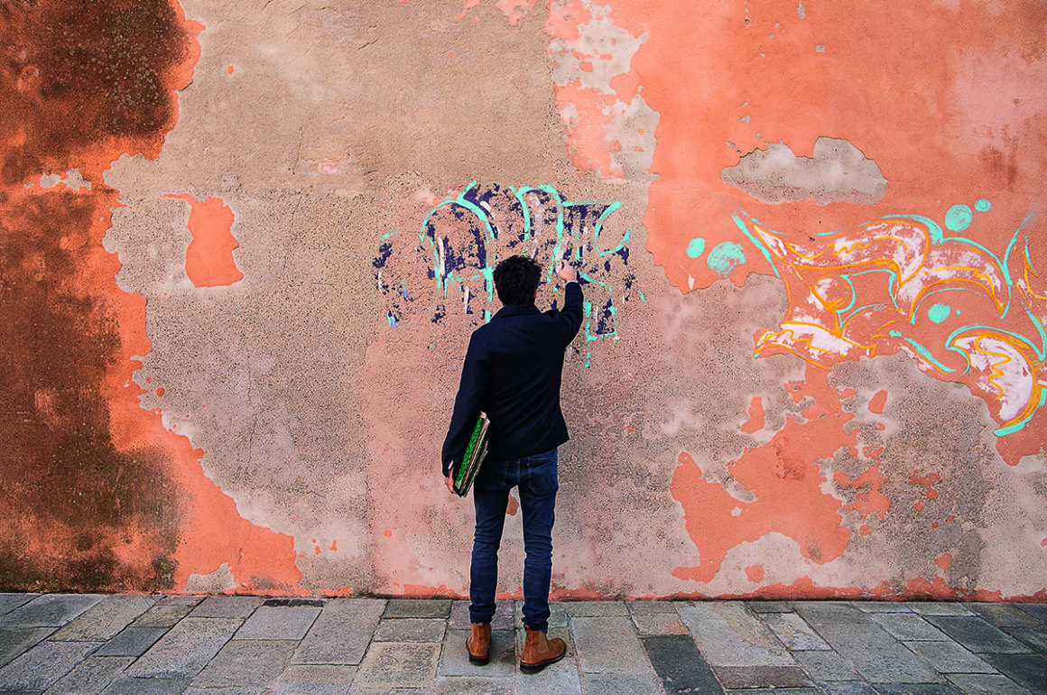 A man painting onto an orange wall