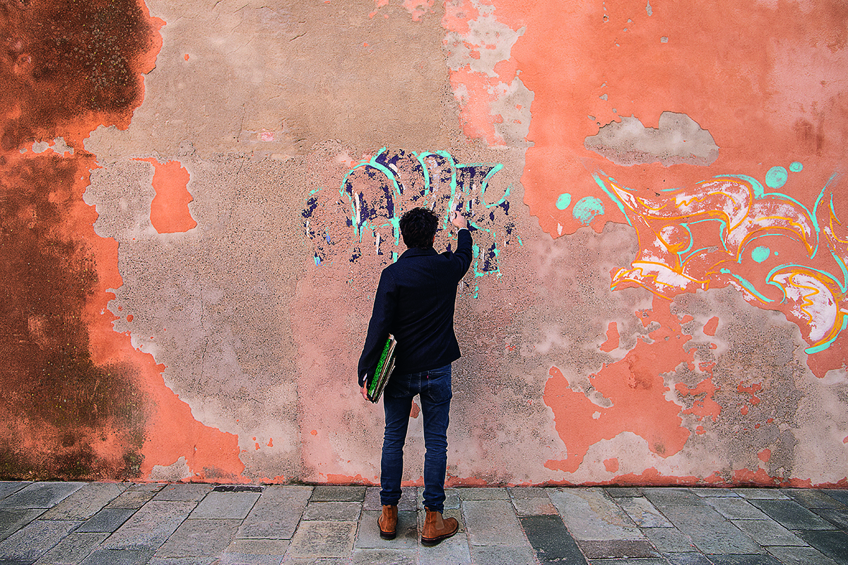 A man painting onto an orange wall