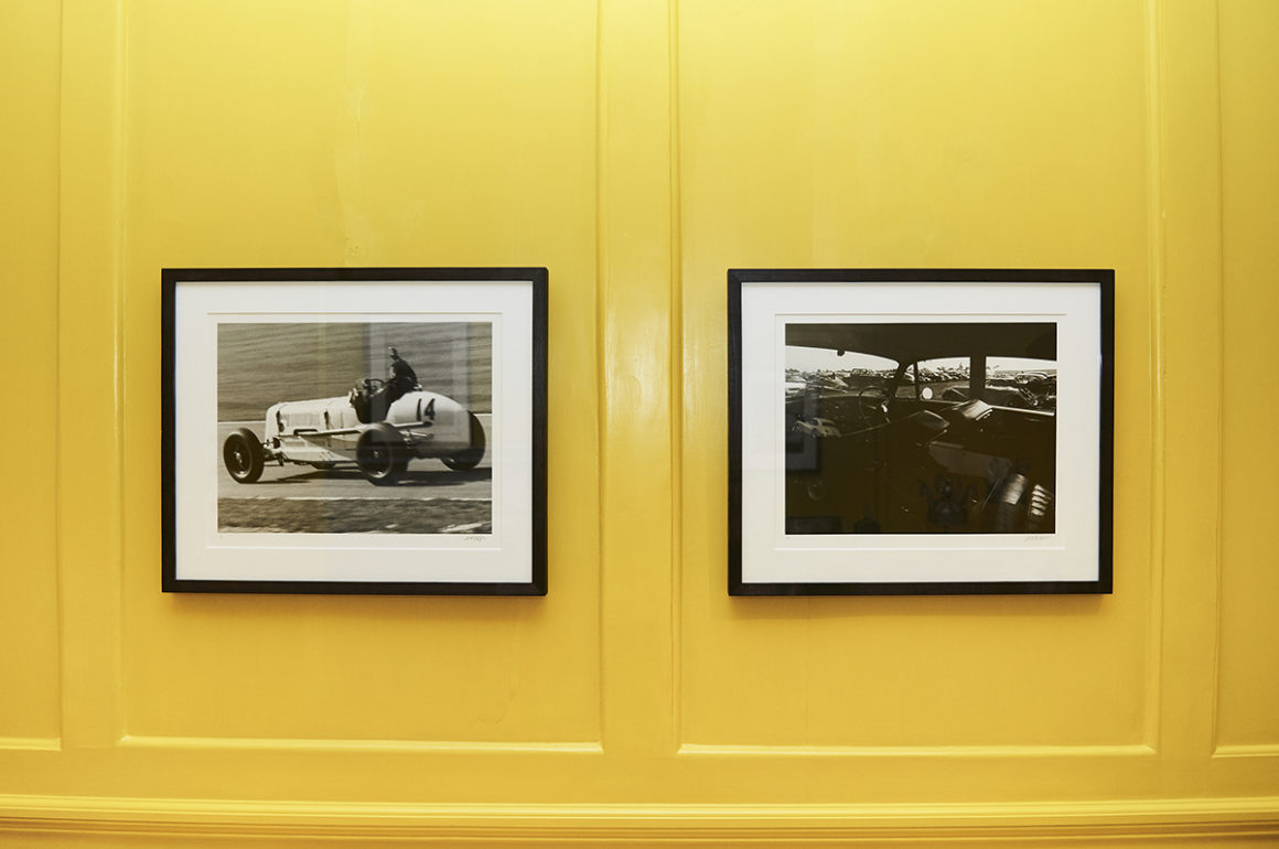 Installation shot of racing car photos in black and white against a yellow wall