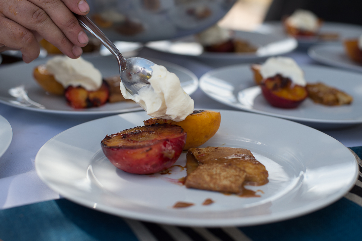 A spoon applying cream to half a cooked peach