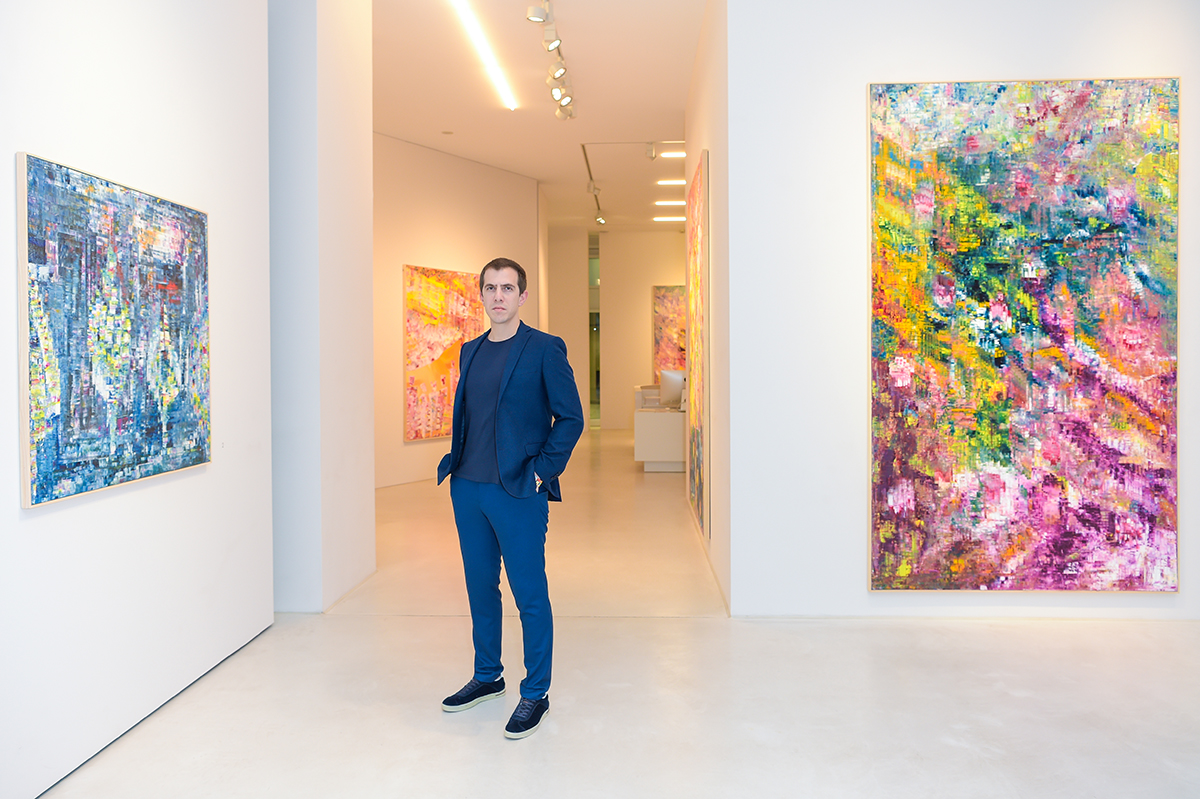 Artist standing amongst work in art gallery