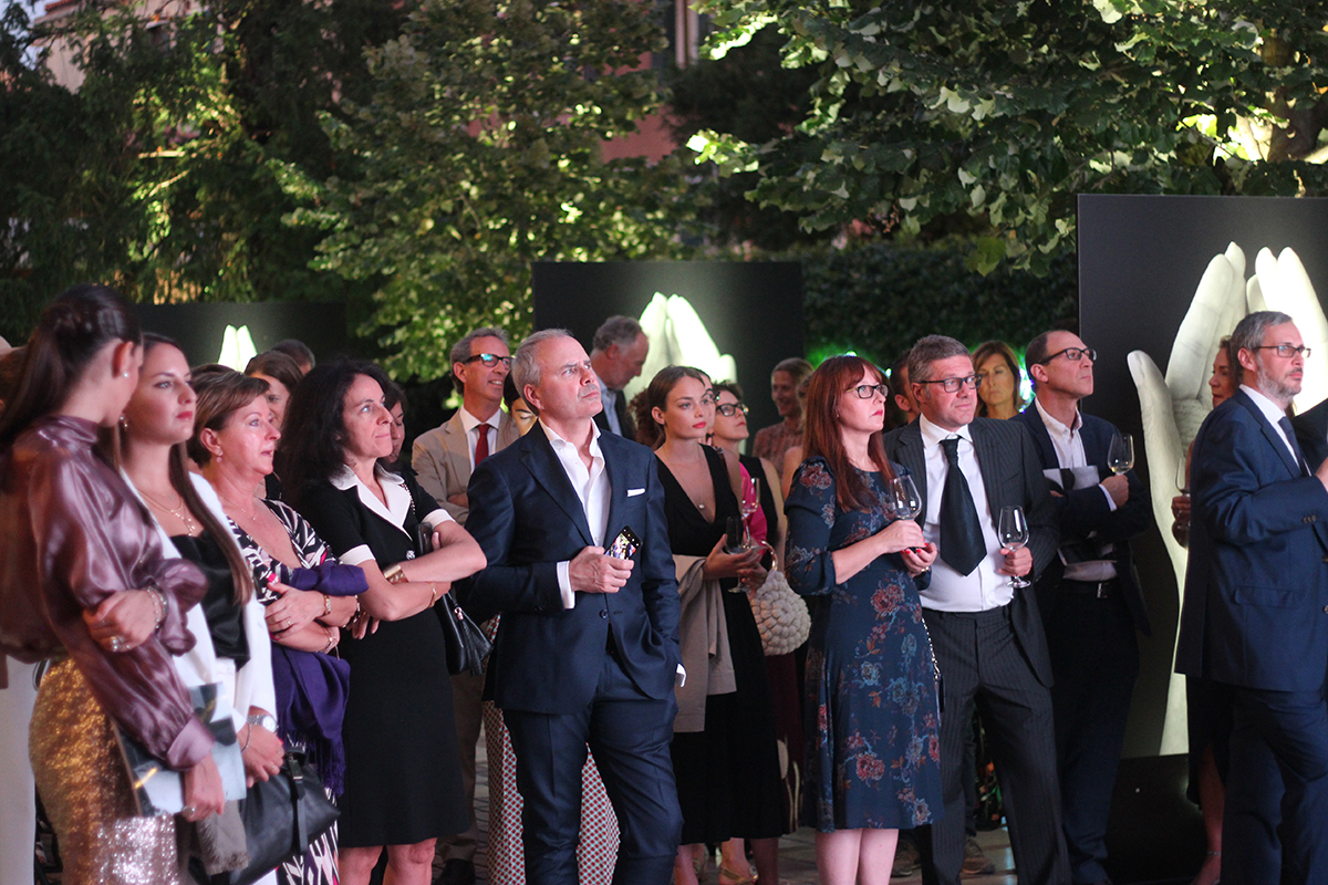 Party guests stand in courtyard watching a screen