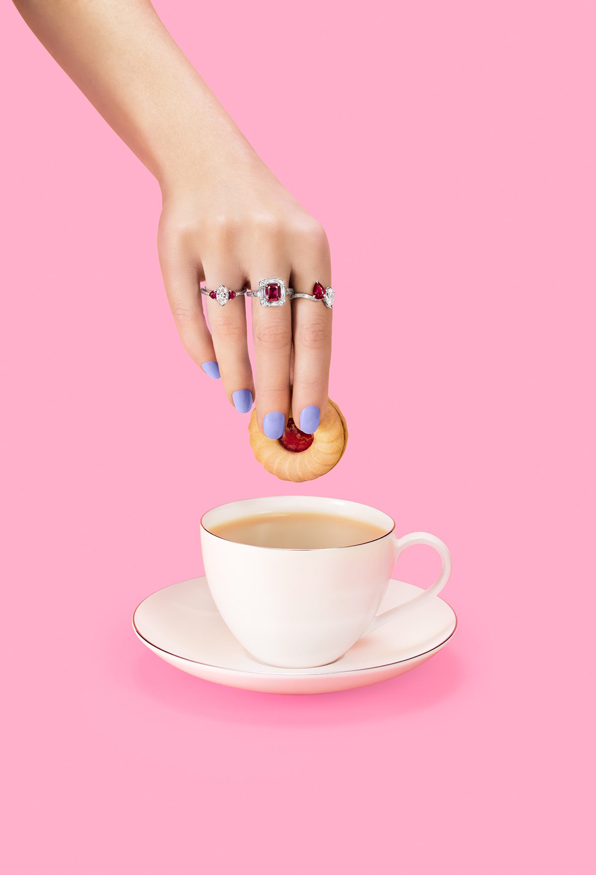 rings on a woman's hand shown dipping biscuit into tea