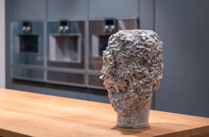 Sculpture of a head standing on a counter in a kitchen