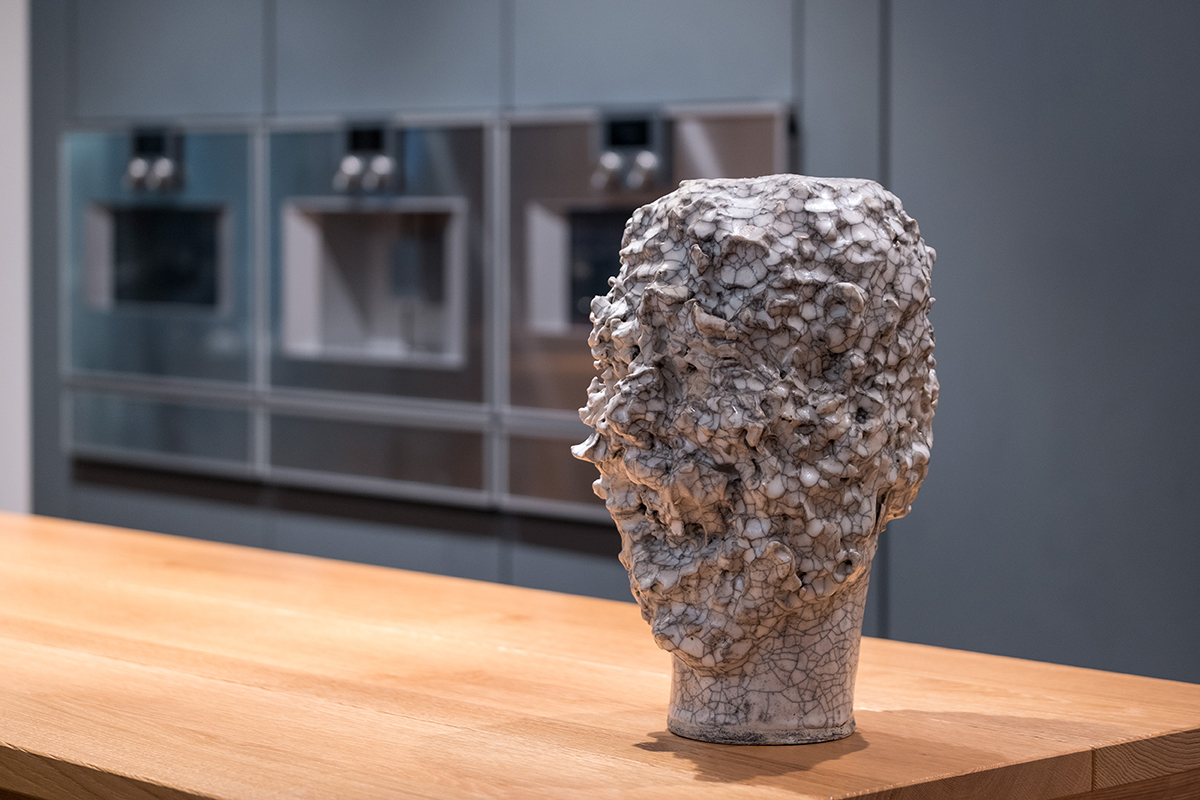 Sculpture of a head standing on a counter in a kitchen