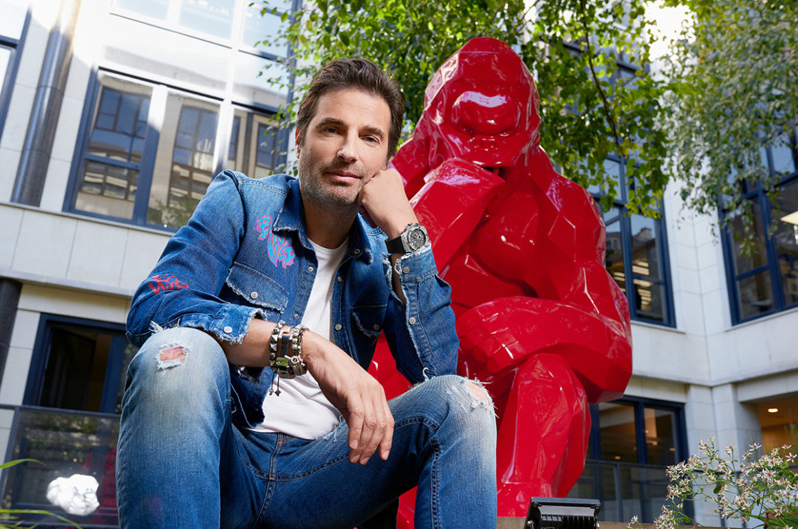 Artist sitting by sculpture of a gorilla