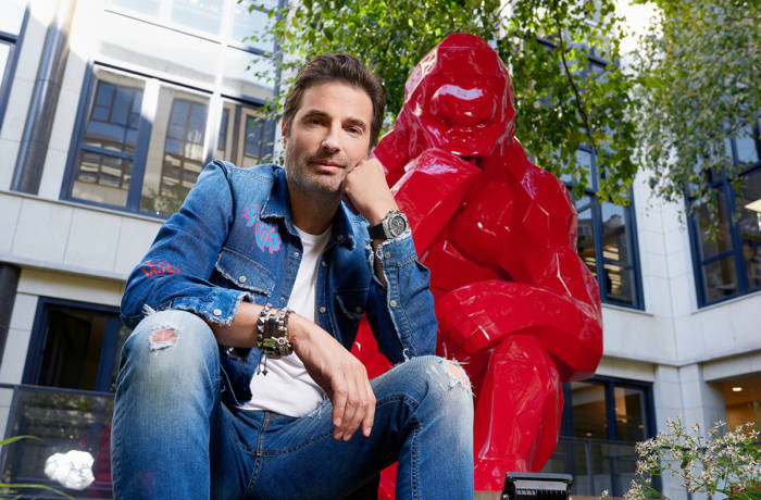 Artist sitting by sculpture of a gorilla