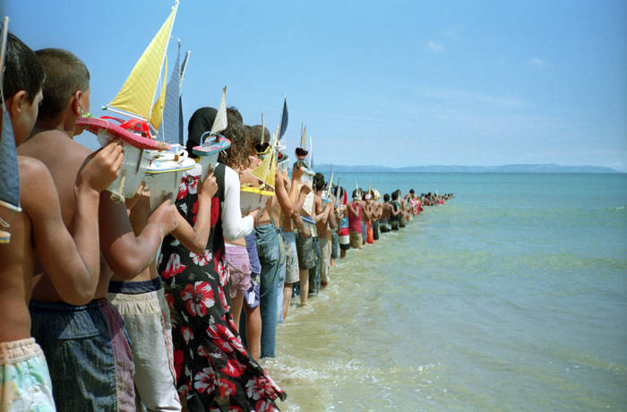 People standing in water holding boats