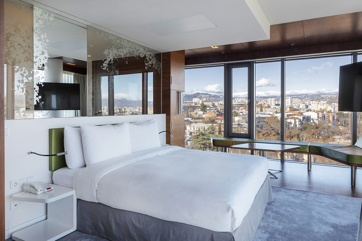 Luxurious hotel bedroom with floor to ceiling glass windows