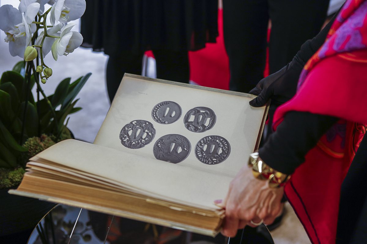 Woman holding open a book with pictures of silver pendants