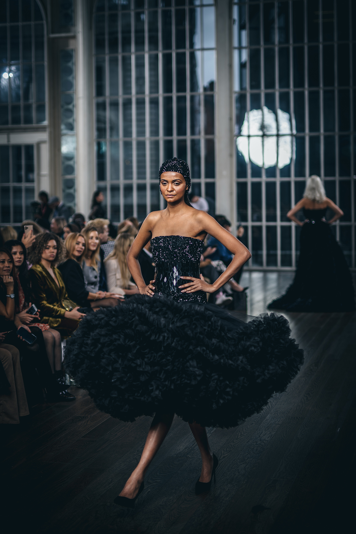 Model on catwalk wearing black feathered dress