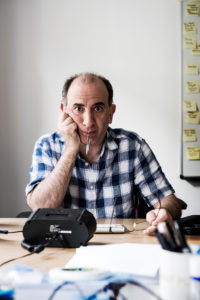 Man sitting at desk with pen in his mouth