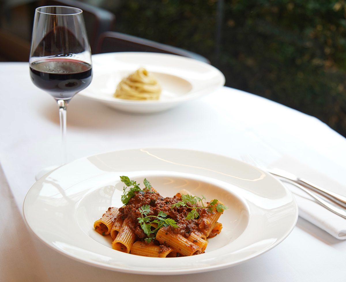 Bowl of pasta and wine on table