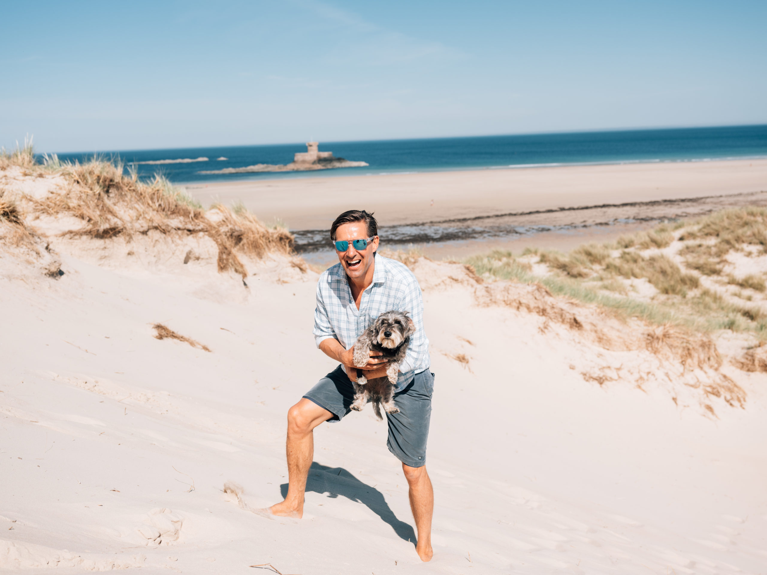 man holding dog on the beach
